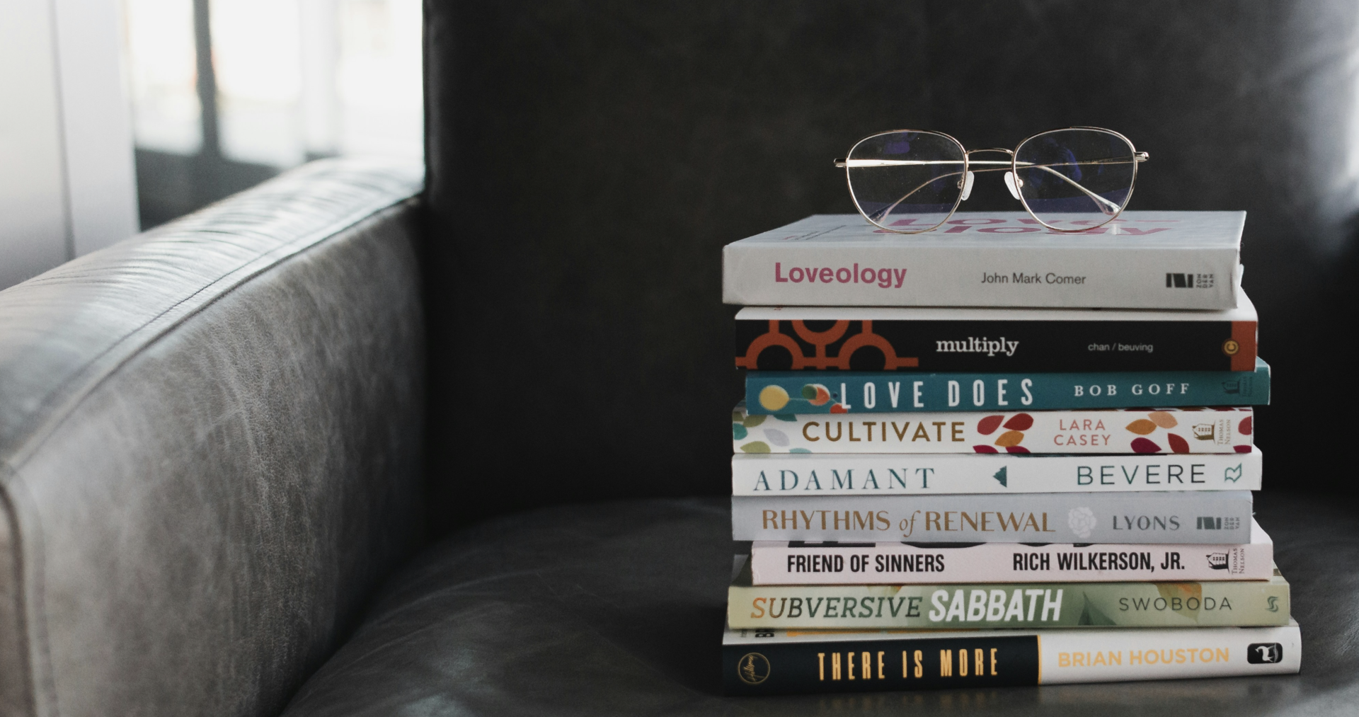 가죽 의자 위에 쌓인 책과 그 위에 놓인 안경